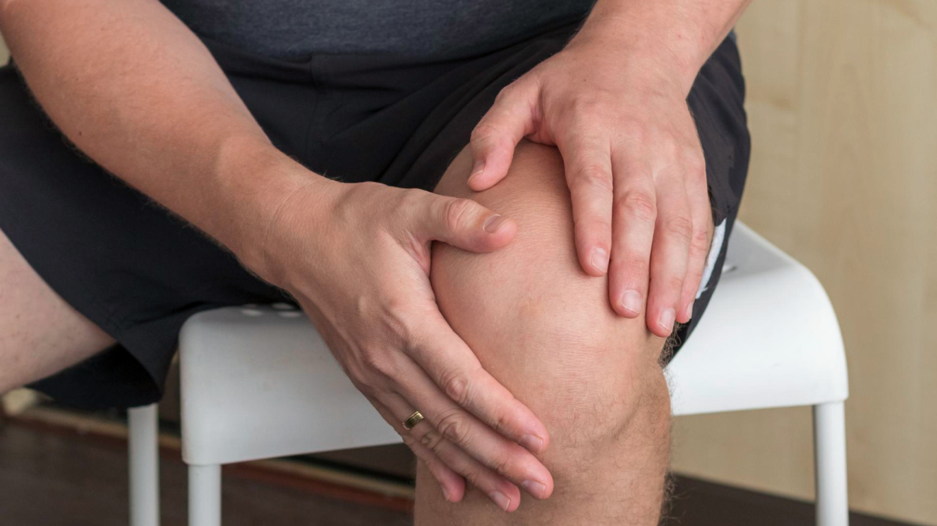 Homem obeso com as mãos nos joelhos, preocupado com as dores articulares e o sobrepeso