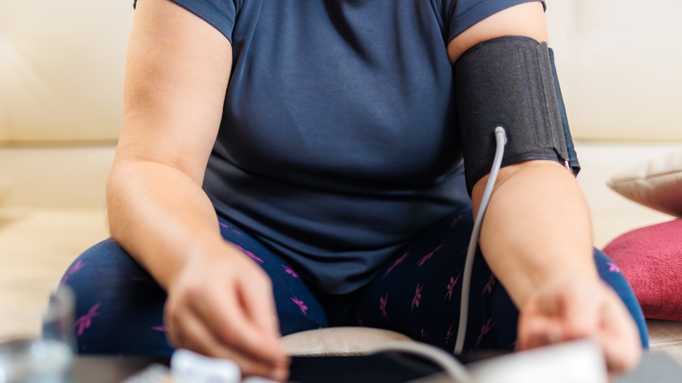 Mulher aferindo a pressão, pensando em obesidade e hipertensão