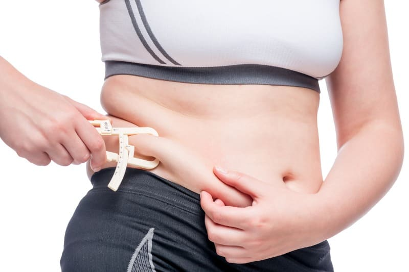 Mulher medindo a gordura abdominal, pensando na cirurgia bariátrica