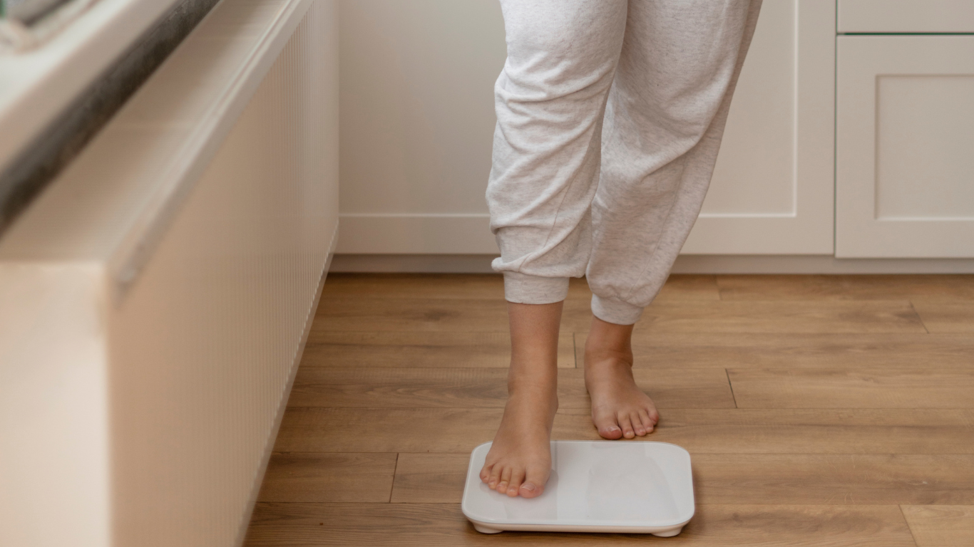 Mulher subindo na balança, pensando no reganho de peso após a cirurgia bariátrica
