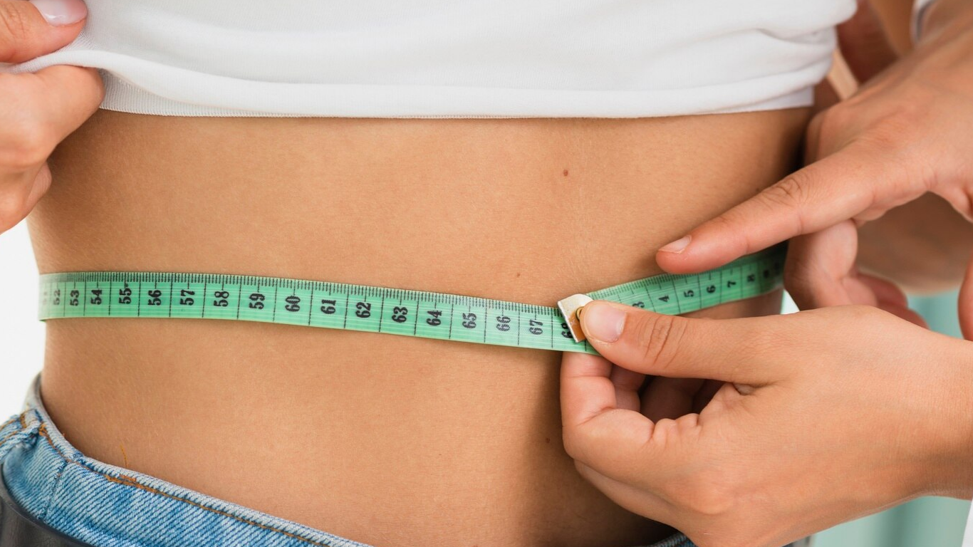 Médico medindo a circunferência abdominal da paciente, explicando a relação entre IMC e bariátrica