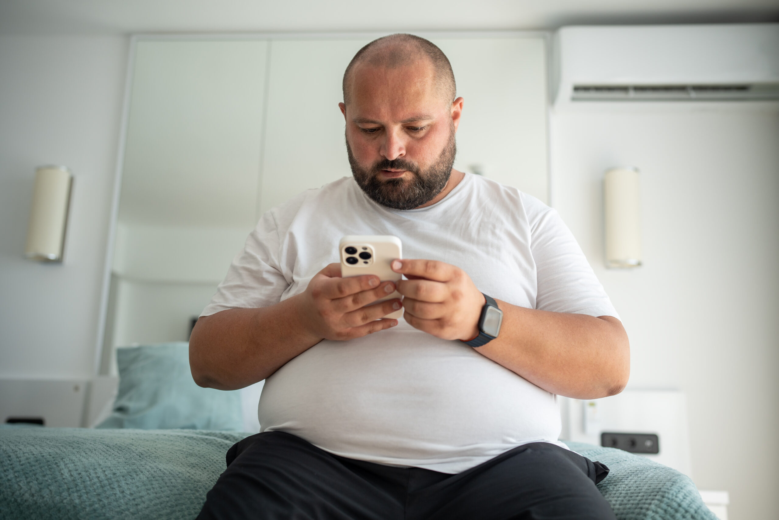 Homem com obesidade pesquisando no celular quais os pontos negativos de uma bariátrica.