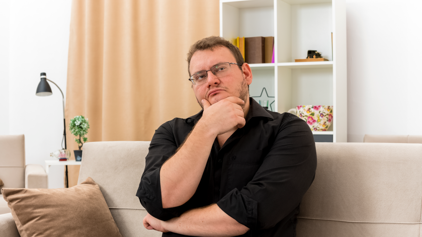 Homem obeso no sofá pensando em quando fazer a cirurgia bariátrica