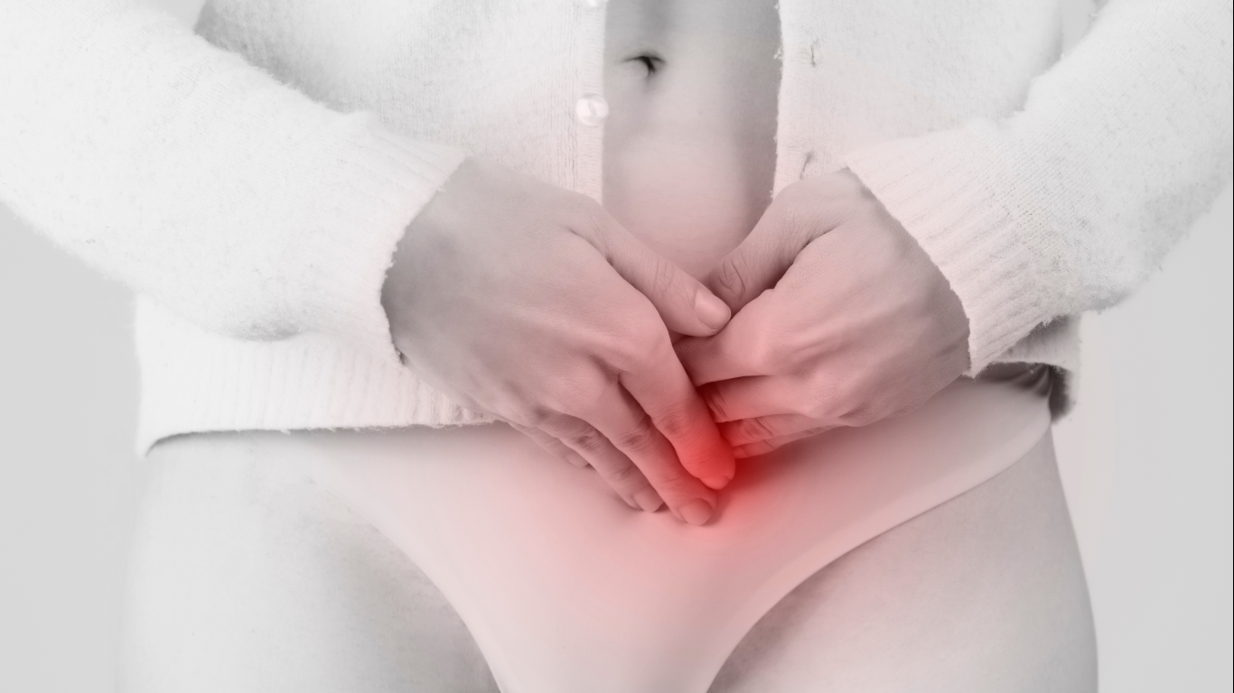 Mulher com as mãos no ventre, para falar sobre a hérnia inguinal feminina