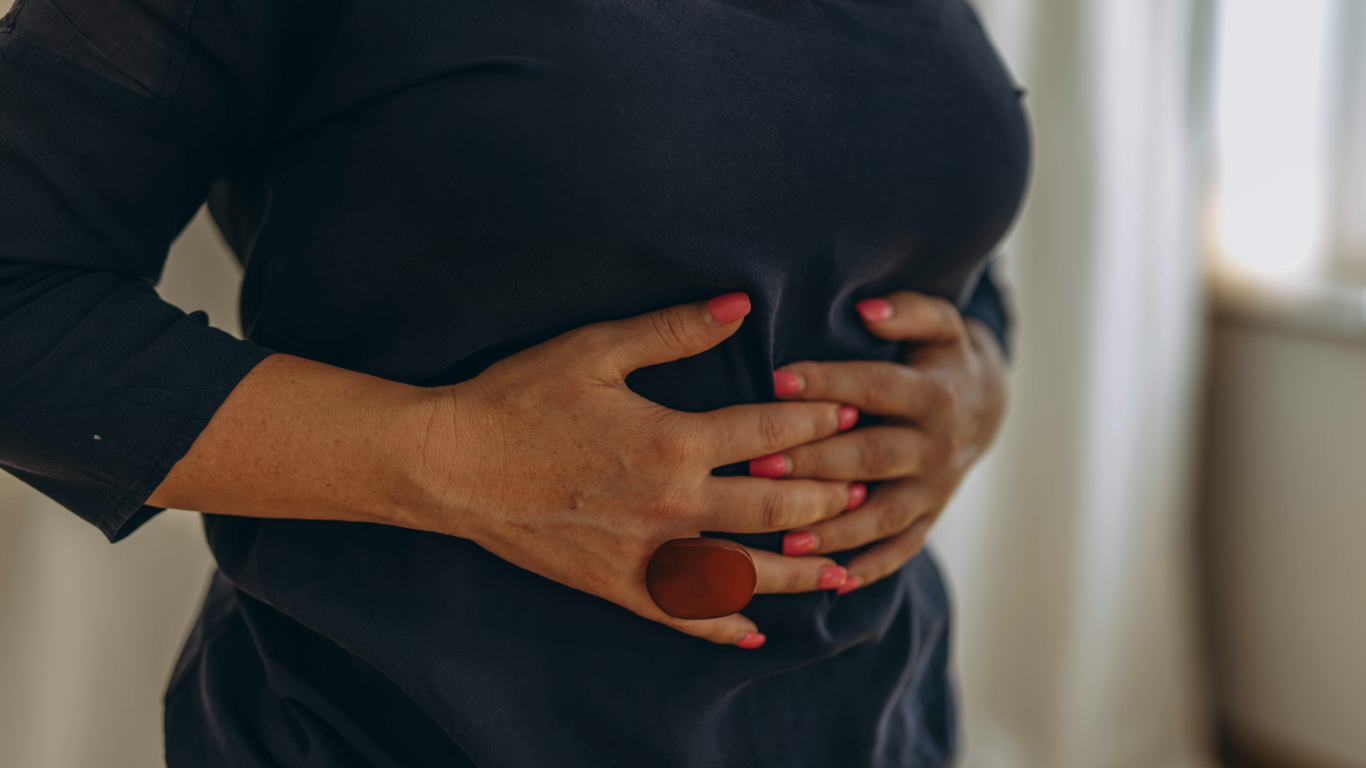 Mulher com as mãos no abdome, para falar sobre o uso de tela para hérnia